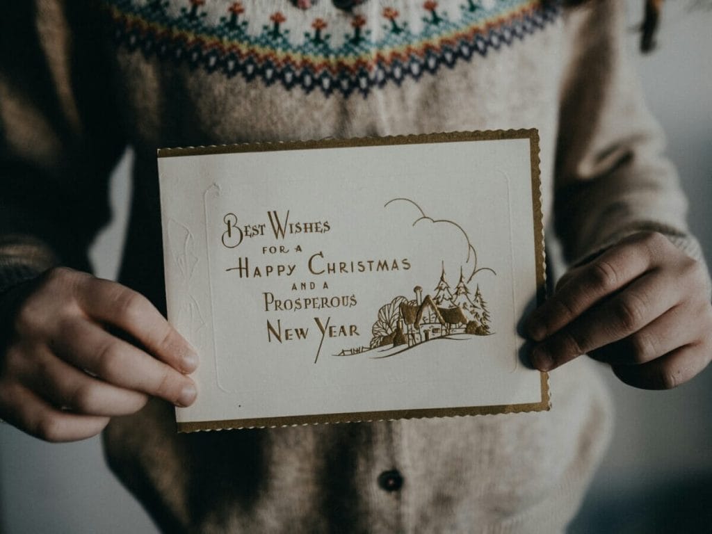Person holding a vintage Christmas card with a holiday message