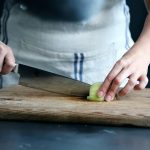 Close-up of hands chopping an onion on a wooden board—highlighting efficient meal prep in a modern kitchen