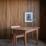 Minimalist wooden desk and chair against vertical wood paneling