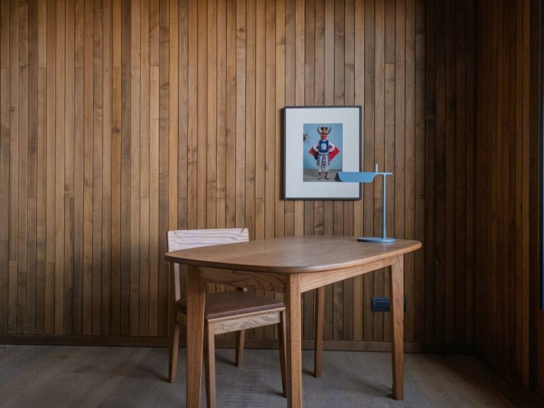 Minimalist wooden desk and chair against vertical wood paneling