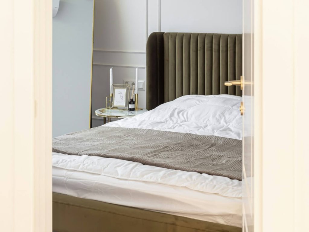 Bed floating in center of square room with large windows and neutral decor