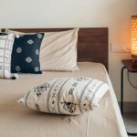 Small bedroom with bed pushed against wall and accent pillows