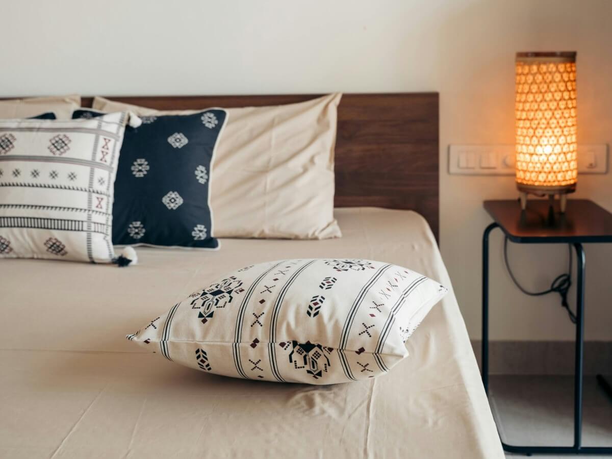 Small bedroom with bed pushed against wall and accent pillows