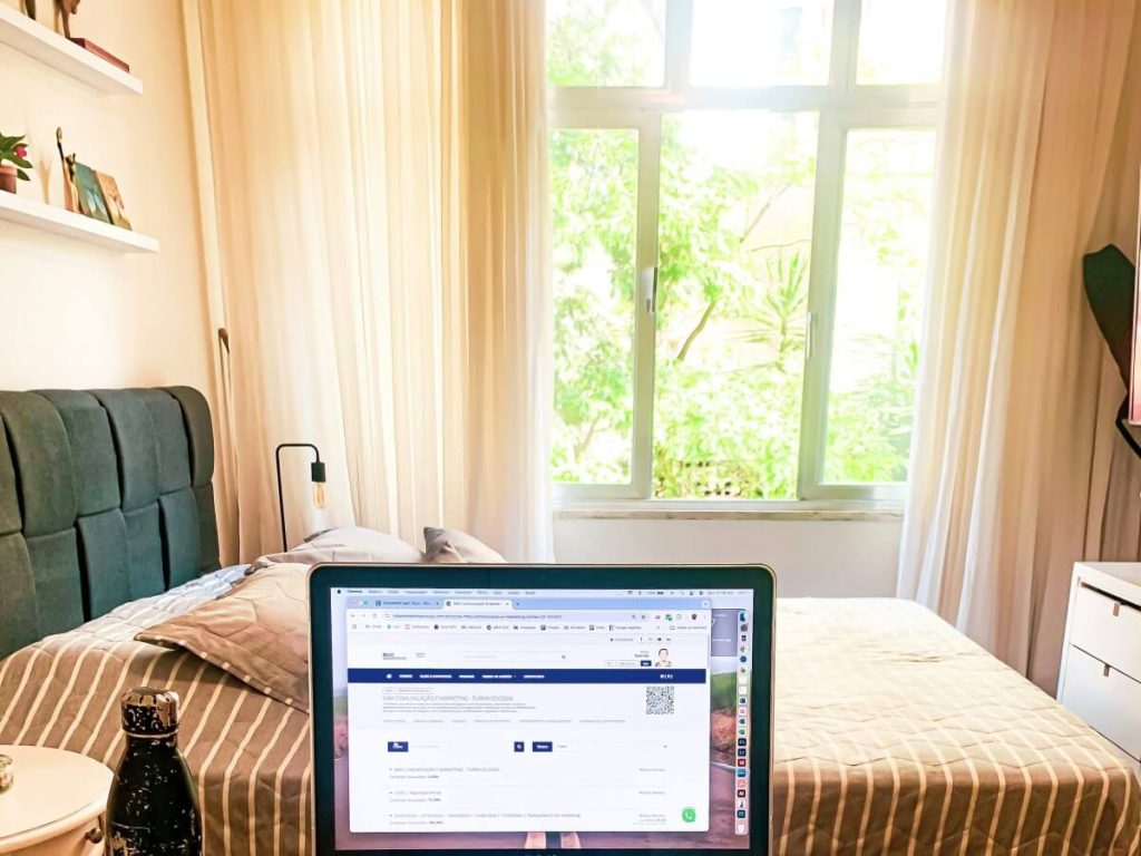 Small bedroom with bed under wide window and sheer curtains