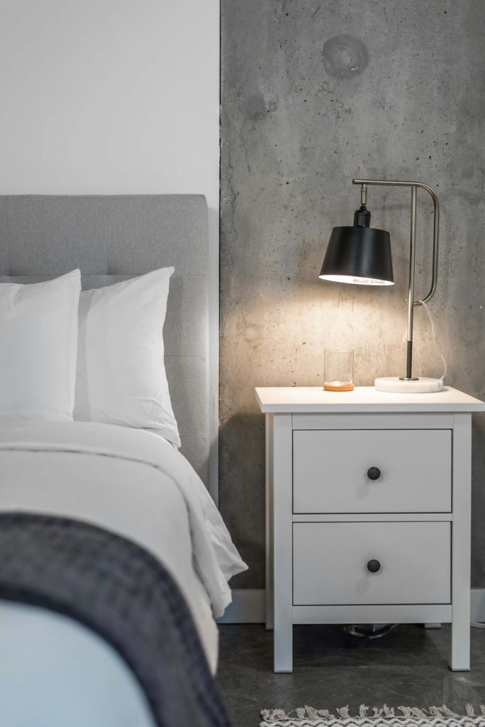 A bedroom with a bed nightstand and lamp by Suzanne Rushton