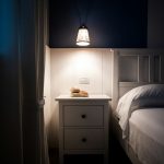A minimalist white nightstand next to a double bed by Lu