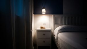 A minimalist white nightstand next to a double bed by Lu