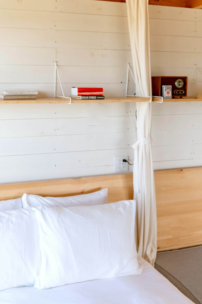 A cozy cabin bedroom with cream walls and vintage bookshelf by Andrea Davis