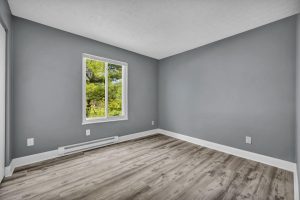 An apartment bedroom with gray walls and a single window by Josh Lemmon