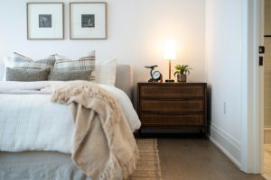 A modern bedroom with a dark wooden bedside table